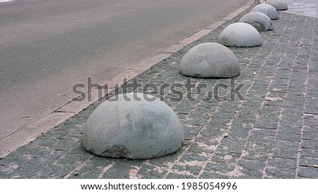 Gray concrete anti-parking hemispheres at the sidewalk