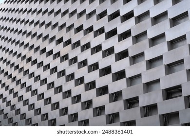 A gray concrete building with a staggered pattern of rectangular windows and balconies. Concept of modern architecture in the city