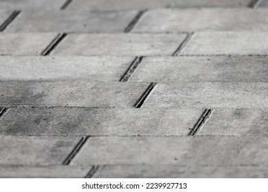 Gray concrete cobble road background, paving slabs close-up photo with selective soft focus