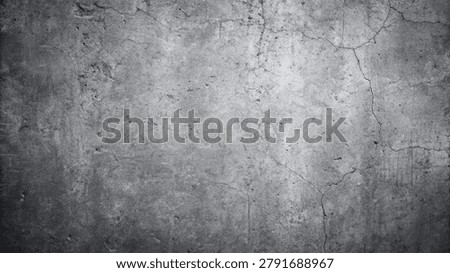 Gray concrete wall texture featuring cracks and a grunge aesthetic. The surface is rough and worn, creating a weathered background.