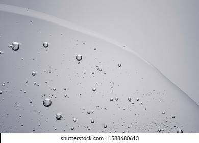 Gray cosmetic liquid gel texture with bubbles. Clear drop isolated on white background