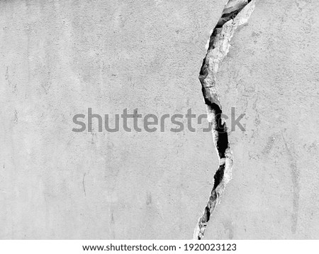 Gray cracked concrete texture background, close up. Big crack on the wall. Black and white. Wall of the house with a huge crack.