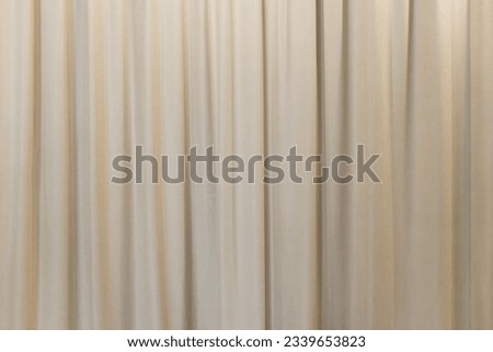 Gray curtain fabric texture and background. Large wall curtain. Curtain for hotel presentations. Cream colored cloth.	