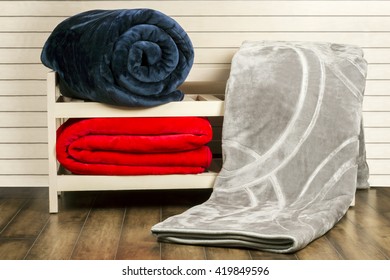 Gray, Dark Blue, Red Winter Blankets On Wooden Shelf Unit