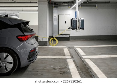 A gray electric car is charging in an underground parking. The concept of ecological energy systems.