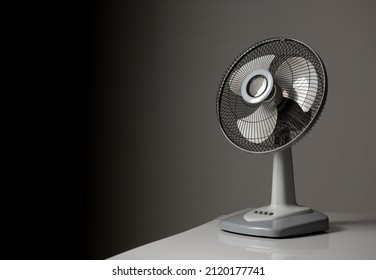 Gray electric fan on white table; Space for text