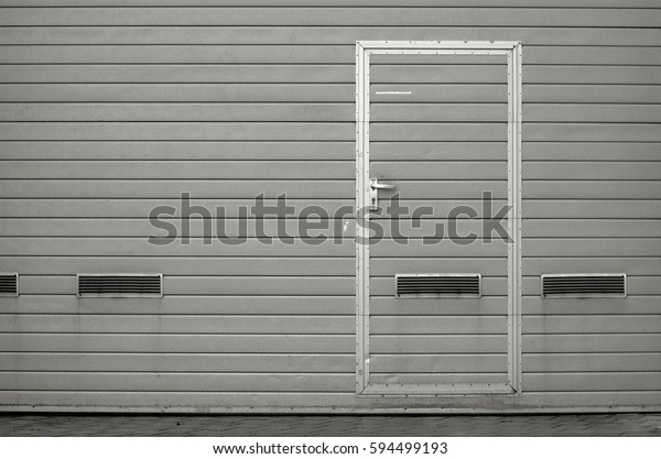 Gray garage gate with ventilation grilles.\
Large automatic up and over garage door with inclusion of smaller\
personal door. Multicolor background\
set