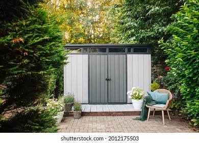 Gray garden shed in summer. Lots of pots of flowers next to a plastic garden shed. Relax in the garden. Big garden in Germany 