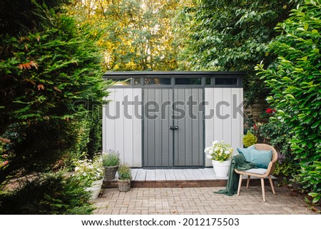 Gray garden shed in summer. Lots of pots of flowers next to a plastic garden shed. Relax in the garden. Big garden in Germany 