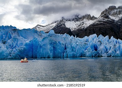 Gray Glacier is a blue glacier in Patagonia, Chile. Boat with tourists floats among icebergs. Huge iceberg has broken off from the Gray Glacier and drifts across the lake. Great Ice of Gray. 