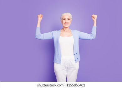 Gray haired old nice beautiful confident cheerful smiling woman showing strength winner gesture sign with arms. Isolated over violet purple background