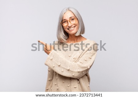 gray haired woman looking excited and surprised pointing to the side and upwards to copy space