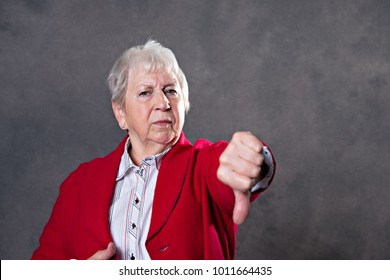 gray hairy elderly woman looking angry and showing thumb down