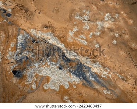 Gray hot bubbling mud pot in a volcano geothermal area, geological phenomena, aerial directly above view. Nature, adventure and destination concepts.