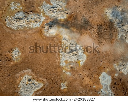 Gray hot bubbling mud pot in a volcano geothermal area, geological phenomena, aerial directly above view. Nature, adventure and destination concepts.