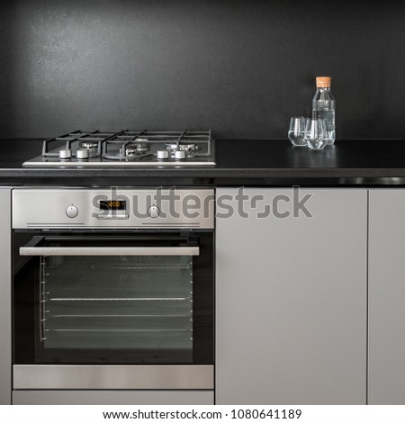 Gray kitchen cabinet, black backsplash, oven and hob