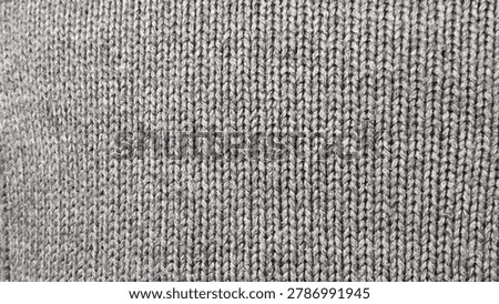 Gray knitted fabric texture background with tight woven stitches, soft textile surface for clothing, design and cozy winter themes.