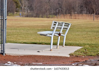 Gray Metal Sports Bench With Rust On Concrete Slab Near Metal Fence Grass Background