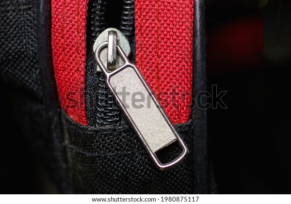 gray\
metal zip on a bag made of black and red\
fabric