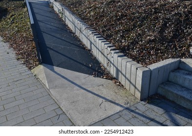 gray monolithic concrete park bench made of concrete in the shape of round stones wooden staircase bench with staircase lighting with metal railing black lattice on the stairs, wheelchair ramp, net - Shutterstock ID 2254912423
