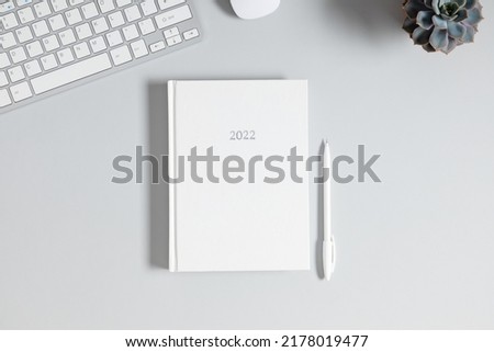 Gray office desk mockup, white book mockup, diary for 2022,, computer keyboard, plant. Flat lay, top view, copy space