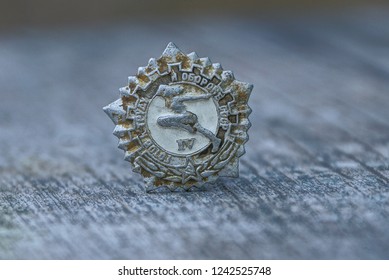 gray old sporting soviet badge on wooden table