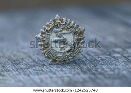 gray old sporting soviet badge on wooden table