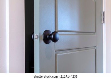 Gray Paneled Hinged Wooden Bedroom Door With Black Door Knob And Visible Latch