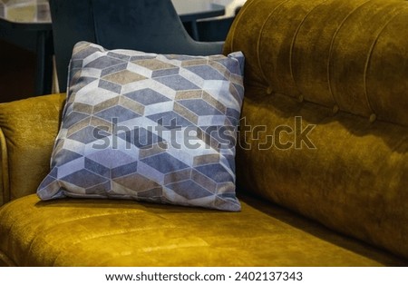 Gray pillow with zigzag pattern lies in corner on yellow comfortable sofa in living room