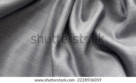 Gray plain weave suiting fabric with a sheen. The texture of the fabric. Light gray textile background.