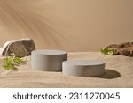 Gray podiums in cylinder and round shape decorated with Feverfew flowers and blocks of stone. Tropical leaf shadow. Stage showcase on minimal podium display