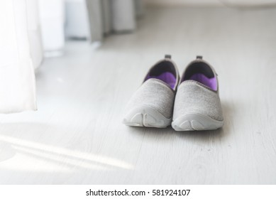 Gray, purple fabric shoes  beside view for walking on wooden gray floor
