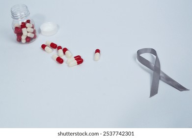 Gray ribbon symbol and some medicine capsules isolated on white background, symbol to commemorate the month of awareness for diabetes and cancer sufferers. Health and medicine concept - Powered by Shutterstock