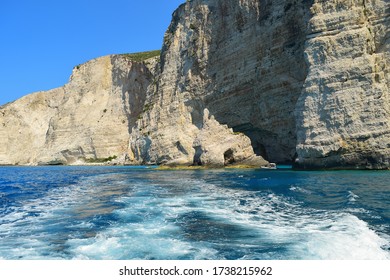 Gray rocks on the blue waters of the Mediterranean Sea in Greece. Motorboat traces on the water