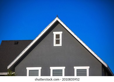 A gray rooftop with attic windows under the sky