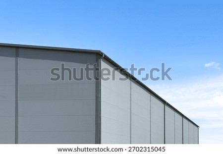 Gray sandwich-panel warehouse facade with gutter
