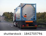 Gray semi truck tanker with 80/2586 dangerous class sign on barrel drive on asphalt highway on a summer day on green trees background, Arylsulfonic acids ADR hazardous cargo logistics, rear view