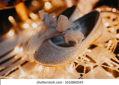 Gray Shiny Holiday Shoes For A Girl With A Tulle Bow Stand On A Garland And Yellow Bulbs