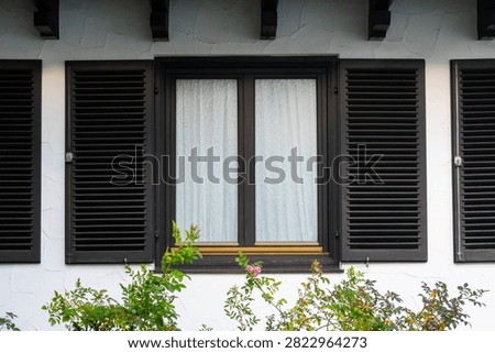Gray shutters on the window on a white wall. Vintage buidling with shutters