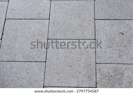 Gray stone pavement texture seen from above, urban flooring background and architectural surface pattern, minimal exterior design.
