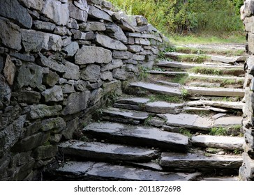 Gray stone stairs with large stone side walls lead to below ground passage way.