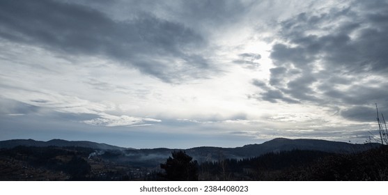 Gray stratus and cumulus clouds float gracefully across the sky, casting gentle shadows across the majestic mountain landscape. The atmosphere is filled with drama