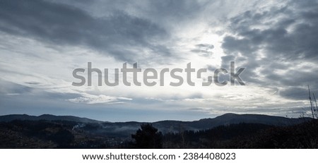 Gray stratus and cumulus clouds float gracefully across the sky, casting gentle shadows across the majestic mountain landscape. The atmosphere is filled with drama