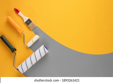 Gray stripes of paint from rollers and brushe on a yellow background. Home renovation concept.