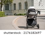 A gray stroller for a newborn baby stands in a summer green park