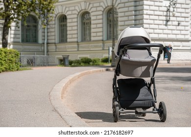 A Gray Stroller For A Newborn Baby Stands In A Summer Green Park