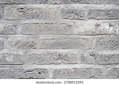 Gray structural stone wall of the ancient building consists of bricks. Nature structural background.