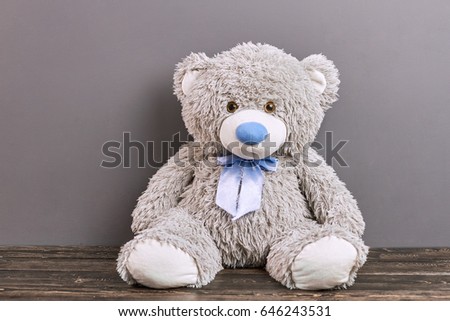 Gray teddy bear. Soft toy on wooden surface.