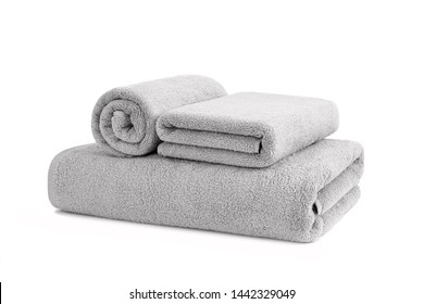 Gray terry towels rolled, folded and stacked isolated.Terry towels against white backdrop. Folded and rolled soft bath towels. Stack of grey cotton towels on a white background