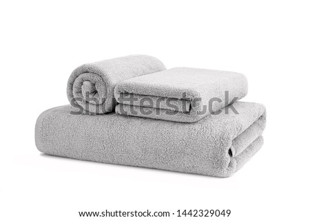Gray terry towels rolled, folded and stacked isolated.Terry towels against white backdrop. Folded and rolled soft bath towels. Stack of grey cotton towels on a white background